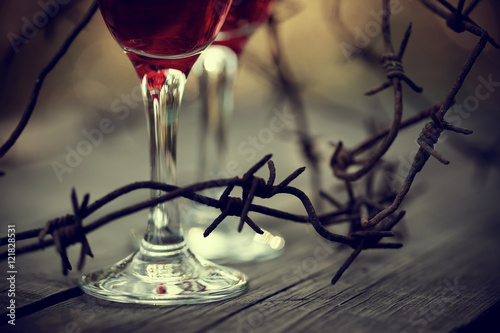 Fotografía Rusty barbed wire and glasses with red wine.