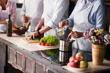 Family and friends cooking food at dinner table