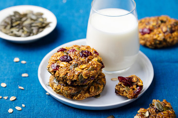 Wall Mural - Pumpkin, oat cookies with cranberries, maple glaze and glass of milk on a blue textile background.
