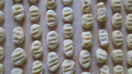 Wall Mural - Potato gnocchi on wood table, overhead shot.