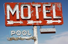 Low Angle View Of Abandoned Motel And Pool Signs Against Sky
