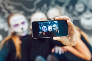 Wall Mural - Three girls going on Halloween, grimace make selfie  a dark background with  pattern