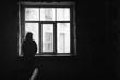 © Studio Dagdagaz - Concept of loneliness in the city, waiting and decision making. Woman looking out of the window in dark deserted house, Selective focus. Special light.