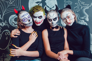 Wall Mural - Three girls and a guy with Halloween face art on dark background pattern