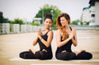 © rilueda - Two beautiful women doing yoga outdoors in an urban neighbourhoo