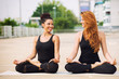 © rilueda - Two beautiful women doing yoga outdoors in an urban neighbourhoo