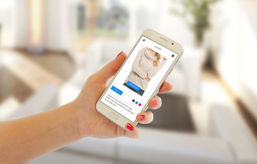 Poster - Woman buy clothes with shopping app. Modern white smart phone in hand, room interior in background.