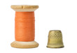 Orange thread spool and thimble isolated on white