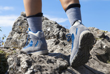 Close Up Of Hiking Boots And Legs Climbing Up Rocky Trail And Reaching The Top Of A Mountain