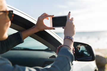 Wall Mural - happy young woman in car with smartphone at sea