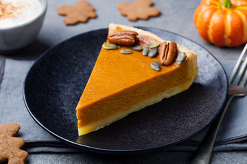 Wall Mural - Pumpkin pie, tart made for Thanksgiving day on a black plate. Grey stone background
