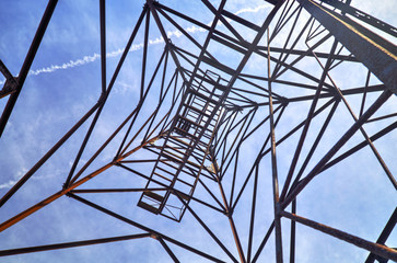 Metallic tower up to the clouds in blue sky