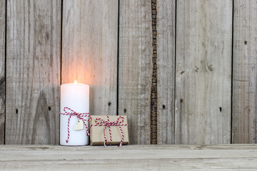 Wall Mural - White candle and present by rustic wood background