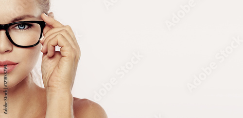 Cuadros en Lienzo Closeup portrait of young beautiful woman face in spectacles over pink background with copy space