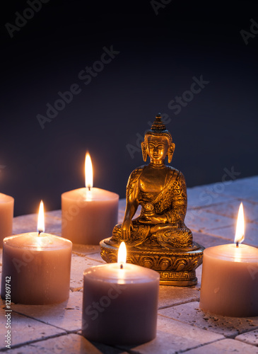Obraz na plátně bronze Buddha with warm lighted candles for concept of mindfulness