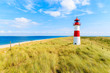Ellenbogen lighthouse on sand dune against blue sky with white clouds on northern coast of Sylt island, Germany