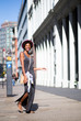 Portrait of fashionable woman walking on city street and smiling