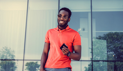 Wall Mural - African male in red shirt using a smartphone.