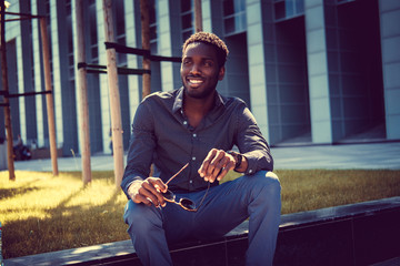 Wall Mural - African American male sits over modern building background.