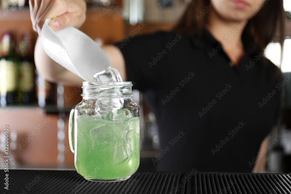 Woman hands adding ice into cocktail on bar counter