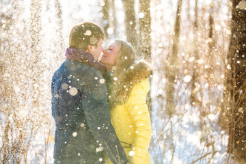 A loving couple walking in winter park. The snowfall