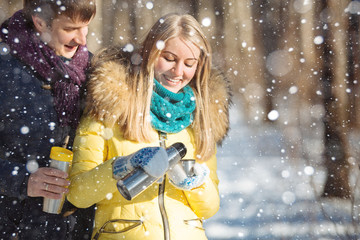 A loving couple walking in winter park. The snowfall