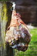 © Mint Images - Close up of a cured ham hanging on a wooden fence.