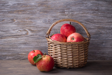 Fresh apple harvest in a wicker basket on a wooden surface, rustic style