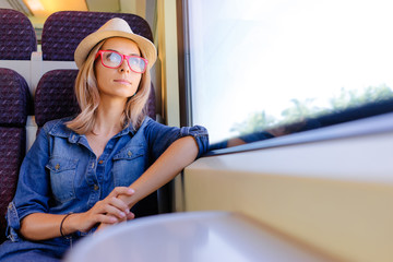 Enjoying travel. Young pretty woman traveling by the train sitting near the window.