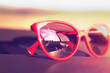 © sunlike - Red sunglasses on the car dashboard with reflection of the sun.