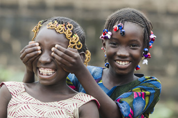 african girls playing peekaboo outdoors laughing and smiling together (happiness symbol)