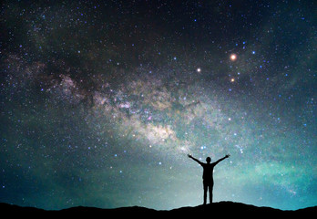 landscape with milky way galaxy. night sky with stars and silhouette happy man on the mountain.