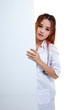 © halfbottle - Young Asian female doctor peeking from behind blank sign billboa