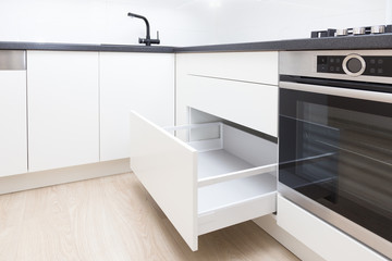 Opened white drawer in a kitchen cabinet with an handleless front, tip to open system