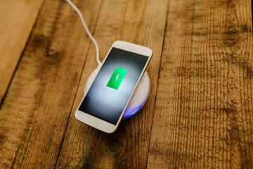 White smartphone charging on a charging pad.