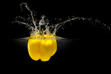 Fototapeta  - Yellow bell pepper falling in water with splash on black background
