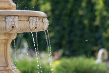 Close-up Of An Old Stone Fountain With Dripping Water And Blurred Background