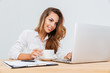 © Drobot Dean - Cheerful businesswoman with cup of coffee sitting and using laptop
