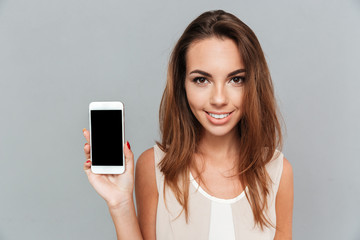 Wall Mural - Portrait of a smiling woman showing blank smartphone screen