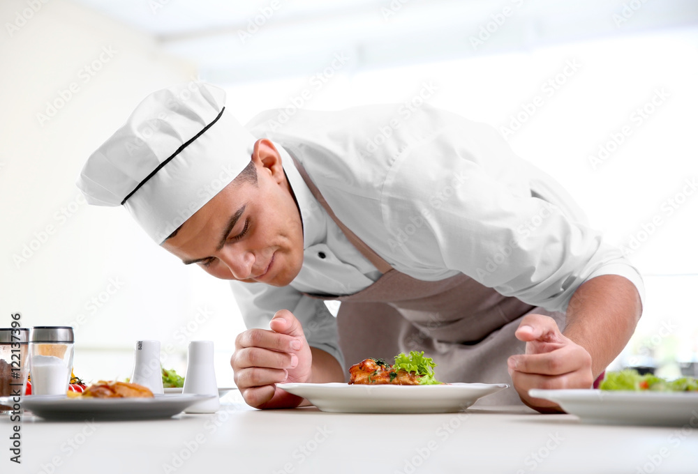 Young chef cook decorating meat dish in kitchen