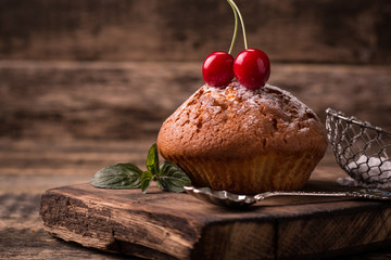 Wall Mural - Tasty muffin with cherry and mint on vintage wooden background