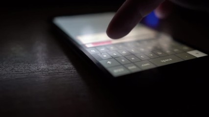 Man checking facebook via smartphone display touchscreen at night.