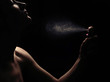 © alexugalek - Young woman with spraying perfume on black background