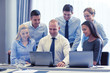 © Syda Productions - smiling businesspeople with laptops in office