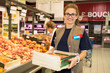 Happy female worker in supermarket holding a large wooden tray
