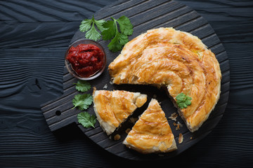 Wall Mural - Burek pie with meat over black wooden background, above view