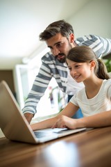 Father and daughter using laptop in the living room 