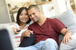 © goodluz - Couple at home in sofa watching movie on tv