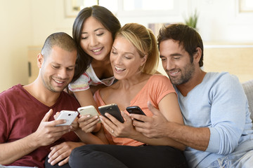 Wall Mural - Friends at home playing with smartphones, connecting people