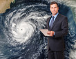 Handsome television meteorologist weatherman with tablet forcasting storm with hurricane image in background 